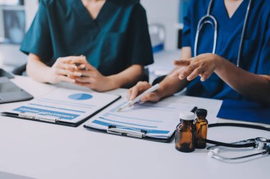 Medical team meeting analyzing blood test results in hospital laboratory. Doctors and scientists in lab coats are having a discussion about blood test result, holding test tubes and taking notes.
