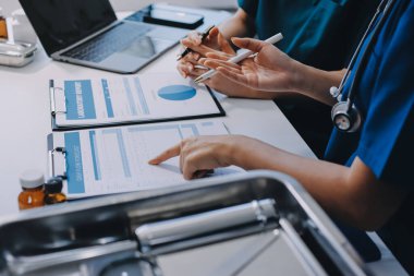 Medical team meeting analyzing blood test results in hospital laboratory. Doctors and scientists in lab coats are having a discussion about blood test result, holding test tubes and taking notes.