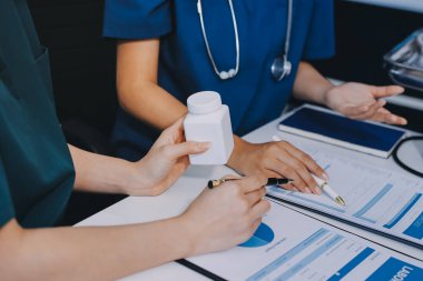 Medical team meeting analyzing blood test results in hospital laboratory. Doctors and scientists in lab coats are having a discussion about blood test result, holding test tubes and taking notes.