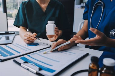 Medical team meeting analyzing blood test results in hospital laboratory. Doctors and scientists in lab coats are having a discussion about blood test result, holding test tubes and taking notes.