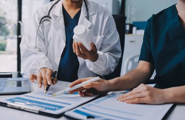 Medical team meeting analyzing blood test results in hospital laboratory. Doctors and scientists in lab coats are having a discussion about blood test result, holding test tubes and taking notes.