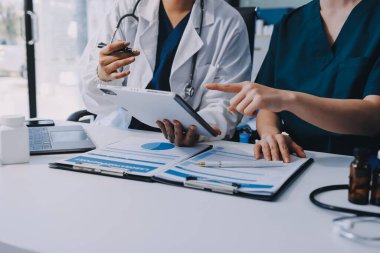 Medical team meeting analyzing blood test results in hospital laboratory. Doctors and scientists in lab coats are having a discussion about blood test result, holding test tubes and taking notes.