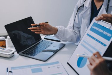 Medical team meeting analyzing blood test results in hospital laboratory. Doctors and scientists in lab coats are having a discussion about blood test result, holding test tubes and taking notes.