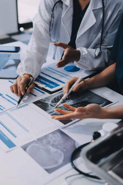 Medical team meeting analyzing blood test results in hospital laboratory. Doctors and scientists in lab coats are having a discussion about blood test result, holding test tubes and taking notes.