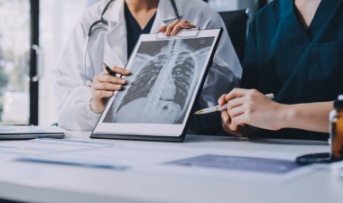 Medical team meeting analyzing blood test results in hospital laboratory. Doctors and scientists in lab coats are having a discussion about blood test result, holding test tubes and taking notes.