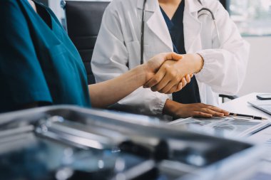 Medical team meeting analyzing blood test results in hospital laboratory. Doctors and scientists in lab coats are having a discussion about blood test result, holding test tubes and taking notes.