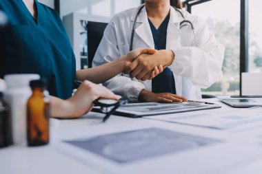 Medical team meeting analyzing blood test results in hospital laboratory. Doctors and scientists in lab coats are having a discussion about blood test result, holding test tubes and taking notes.