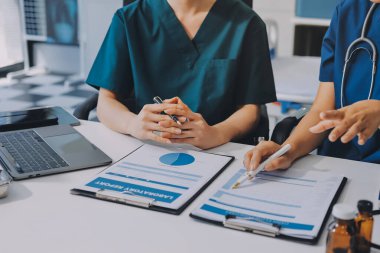 Medical team meeting analyzing blood test results in hospital laboratory. Doctors and scientists in lab coats are having a discussion about blood test result, holding test tubes and taking notes.