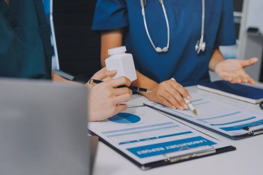 Medical team meeting analyzing blood test results in hospital laboratory. Doctors and scientists in lab coats are having a discussion about blood test result, holding test tubes and taking notes.