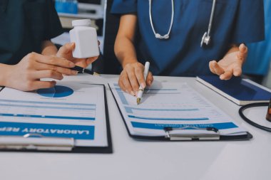 Medical team meeting analyzing blood test results in hospital laboratory. Doctors and scientists in lab coats are having a discussion about blood test result, holding test tubes and taking notes.