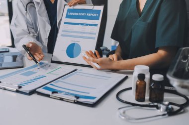 Medical team meeting analyzing blood test results in hospital laboratory. Doctors and scientists in lab coats are having a discussion about blood test result, holding test tubes and taking notes.