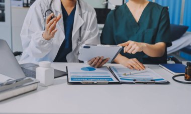 Medical team meeting analyzing blood test results in hospital laboratory. Doctors and scientists in lab coats are having a discussion about blood test result, holding test tubes and taking notes.