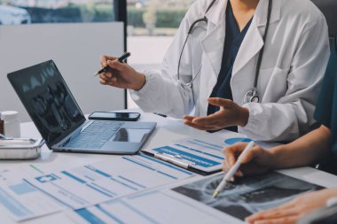 Medical team meeting analyzing blood test results in hospital laboratory. Doctors and scientists in lab coats are having a discussion about blood test result, holding test tubes and taking notes.