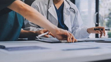Medical team meeting analyzing blood test results in hospital laboratory. Doctors and scientists in lab coats are having a discussion about blood test result, holding test tubes and taking notes.
