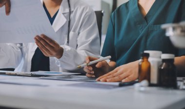 Medical team meeting analyzing blood test results in hospital laboratory. Doctors and scientists in lab coats are having a discussion about blood test result, holding test tubes and taking notes.