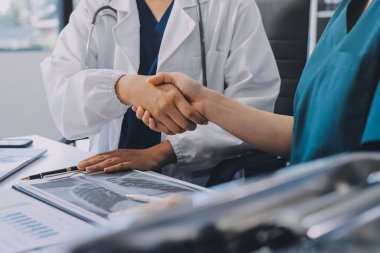 Medical team meeting analyzing blood test results in hospital laboratory. Doctors and scientists in lab coats are having a discussion about blood test result, holding test tubes and taking notes.