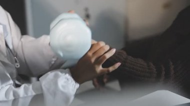 doctor examining patients hand with a patient in hospital.