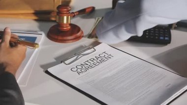 close up of male hands writing on contract with pen on wooden desk