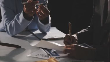 businessman and businesswoman writing documents at table in office