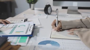 young woman in a white shirt and blue jacket with a pen and a calculator on a wooden table with a pen in the office.
