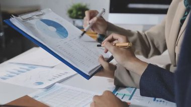 young businessman analyzing graph with his pen on desk