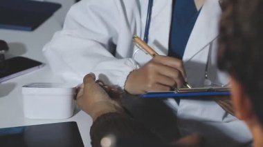 doctor writing prescription to patient in office