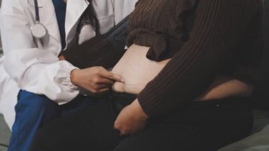 doctor checking pregnant belly with stethoscope