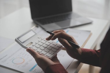 Hesap makinesi ve dizüstü bilgisayarı kullanarak ahşap masa, vergi, muhasebe, istatistik ve analitik araştırma konseptine matematik finansmanı sağlayan İş kadını kapat