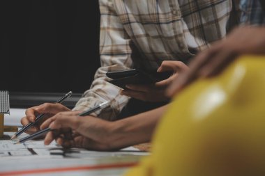 Toplantı odasında inşaat planları üzerinde çalışan çok ırklı mimarlardan oluşan bir ekip. Mühendisler ofiste proje üzerinde tartışıyorlar. Olgun iş adamı ve kadın masanın etrafında durmuş plan üzerinde çalışıyorlar..