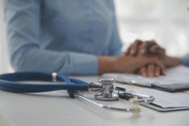 Genç bir kadın kalp ve akciğer kontrolü için kliniğe geliyor. Modern tıp bürosunda masasında oturan, steteskop tutan, hastanın nefesini ya da kalp atışlarını dinleyen ve gülümseyen dost canlısı bir bayan doktor.