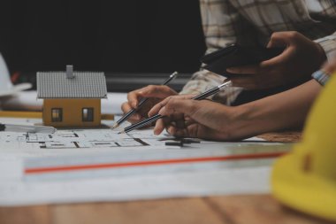 Toplantı odasında inşaat planları üzerinde çalışan çok ırklı mimarlardan oluşan bir ekip. Mühendisler ofiste proje üzerinde tartışıyorlar. Olgun iş adamı ve kadın masanın etrafında durmuş plan üzerinde çalışıyorlar..