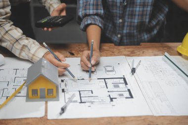 Toplantı odasında inşaat planları üzerinde çalışan çok ırklı mimarlardan oluşan bir ekip. Mühendisler ofiste proje üzerinde tartışıyorlar. Olgun iş adamı ve kadın masanın etrafında durmuş plan üzerinde çalışıyorlar..