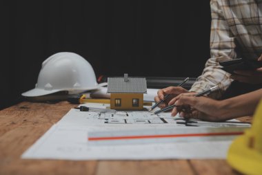 Toplantı odasında inşaat planları üzerinde çalışan çok ırklı mimarlardan oluşan bir ekip. Mühendisler ofiste proje üzerinde tartışıyorlar. Olgun iş adamı ve kadın masanın etrafında durmuş plan üzerinde çalışıyorlar..