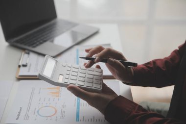 Hesap makinesi ve dizüstü bilgisayarı kullanarak ahşap masa, vergi, muhasebe, istatistik ve analitik araştırma konseptine matematik finansmanı sağlayan İş kadını kapat