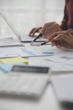 Hesap makinesi ve dizüstü bilgisayarı kullanarak ahşap masa, vergi, muhasebe, istatistik ve analitik araştırma konseptine matematik finansmanı sağlayan İş kadını kapat