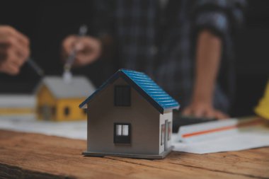 Toplantı odasında inşaat planları üzerinde çalışan çok ırklı mimarlardan oluşan bir ekip. Mühendisler ofiste proje üzerinde tartışıyorlar. Olgun iş adamı ve kadın masanın etrafında durmuş plan üzerinde çalışıyorlar..