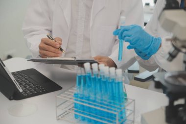 Yaşam bilimi laboratuvarında çalışan sağlık araştırmacıları. Araştırma laboratuarında mikroskop hazırlayan ve analiz eden genç kadın araştırmacı ve kıdemli erkek denetmen..