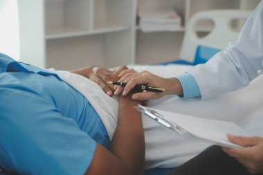 Hastanedeki erkek hastanın yatağının yanında oturan doktora yakın çekim.