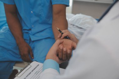 Hastanedeki erkek hastanın yatağının yanında oturan doktora yakın çekim.