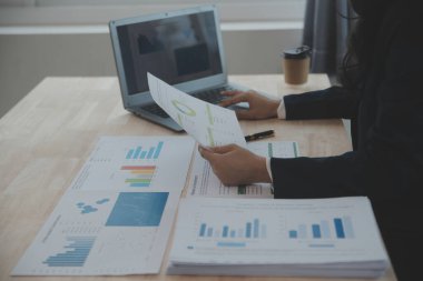 Hesap makinesi ve dizüstü bilgisayarı kullanarak ahşap masa, vergi, muhasebe, istatistik ve analitik araştırma konseptine matematik finansmanı sağlayan İş kadını kapat
