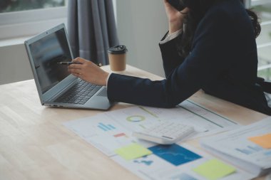 Hesap makinesi ve dizüstü bilgisayarı kullanarak ahşap masa, vergi, muhasebe, istatistik ve analitik araştırma konseptine matematik finansmanı sağlayan İş kadını kapat