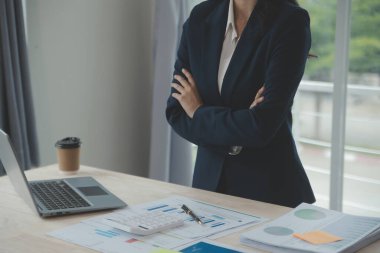 Hesap makinesi ve dizüstü bilgisayarı kullanarak ahşap masa, vergi, muhasebe, istatistik ve analitik araştırma konseptine matematik finansmanı sağlayan İş kadını kapat