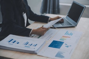 Hesap makinesi ve dizüstü bilgisayarı kullanarak ahşap masa, vergi, muhasebe, istatistik ve analitik araştırma konseptine matematik finansmanı sağlayan İş kadını kapat