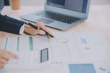 Hesap makinesi ve dizüstü bilgisayarı kullanarak ahşap masa, vergi, muhasebe, istatistik ve analitik araştırma konseptine matematik finansmanı sağlayan İş kadını kapat