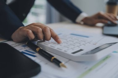 Hesap makinesi ve dizüstü bilgisayarı kullanarak ahşap masa, vergi, muhasebe, istatistik ve analitik araştırma konseptine matematik finansmanı sağlayan İş kadını kapat