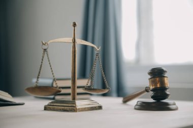 Adalet ve hukuk kavramı. Bir mahkeme salonunda tokmakla çalışan, bilgisayar ve kenetlenme klavyesi, gözlük takan bir erkek yargıç, sabah ışığında masada.