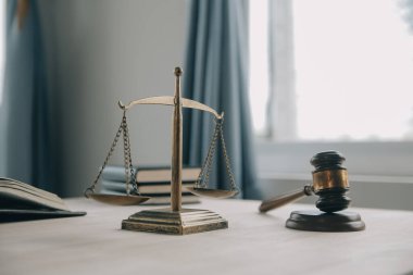 Adalet ve hukuk kavramı. Bir mahkeme salonunda tokmakla çalışan, bilgisayar ve kenetlenme klavyesi, gözlük takan bir erkek yargıç, sabah ışığında masada.