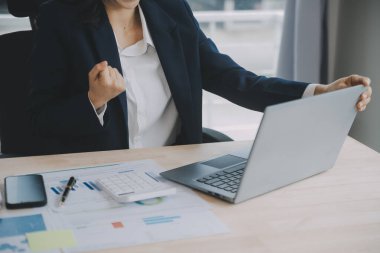 Hesap makinesi ve dizüstü bilgisayarı kullanarak ahşap masa, vergi, muhasebe, istatistik ve analitik araştırma konseptine matematik finansmanı sağlayan İş kadını kapat