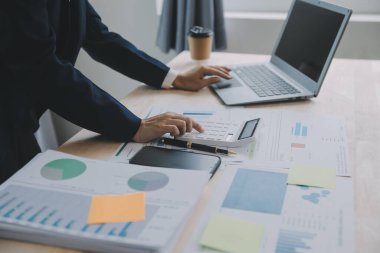 Hesap makinesi ve dizüstü bilgisayarı kullanarak ahşap masa, vergi, muhasebe, istatistik ve analitik araştırma konseptine matematik finansmanı sağlayan İş kadını kapat