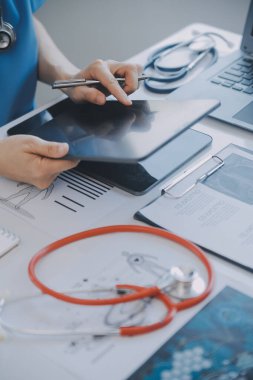 Çok ırklı tıbbi ekip, beyaz laboratuvar önlüklü ve ameliyat önlüklü doktorlarla toplantı yapıyor. Hasta kayıtlarını tartışıyorlar.